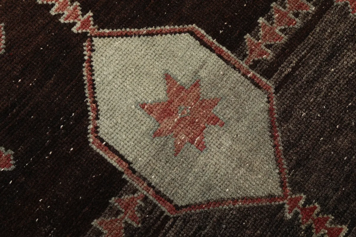 Close-up of an ivory geometric star motif within a black medallion on the rust runner