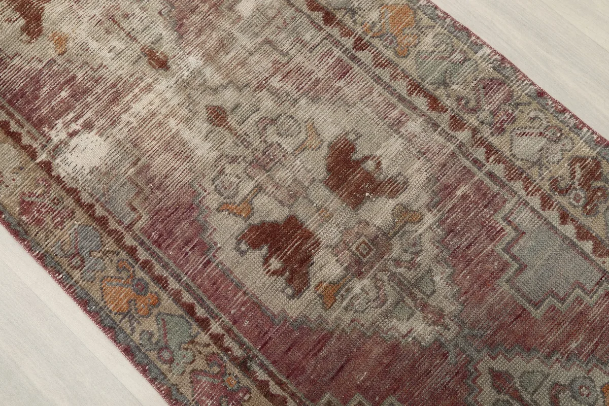 Close-up of the central field, revealing the distressed wool pile and intricate tribal geometric patterns.