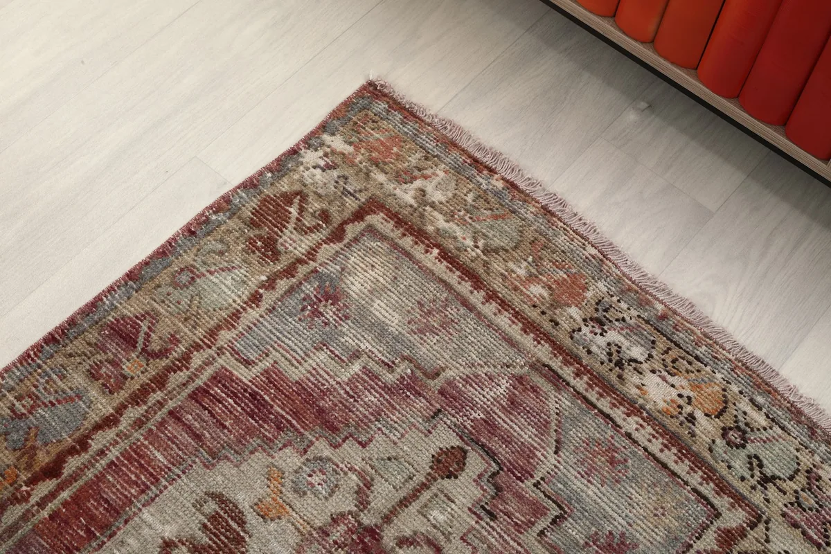 Close-up of the rug's border, highlighting the intricate patterns and the slightly faded fringe.