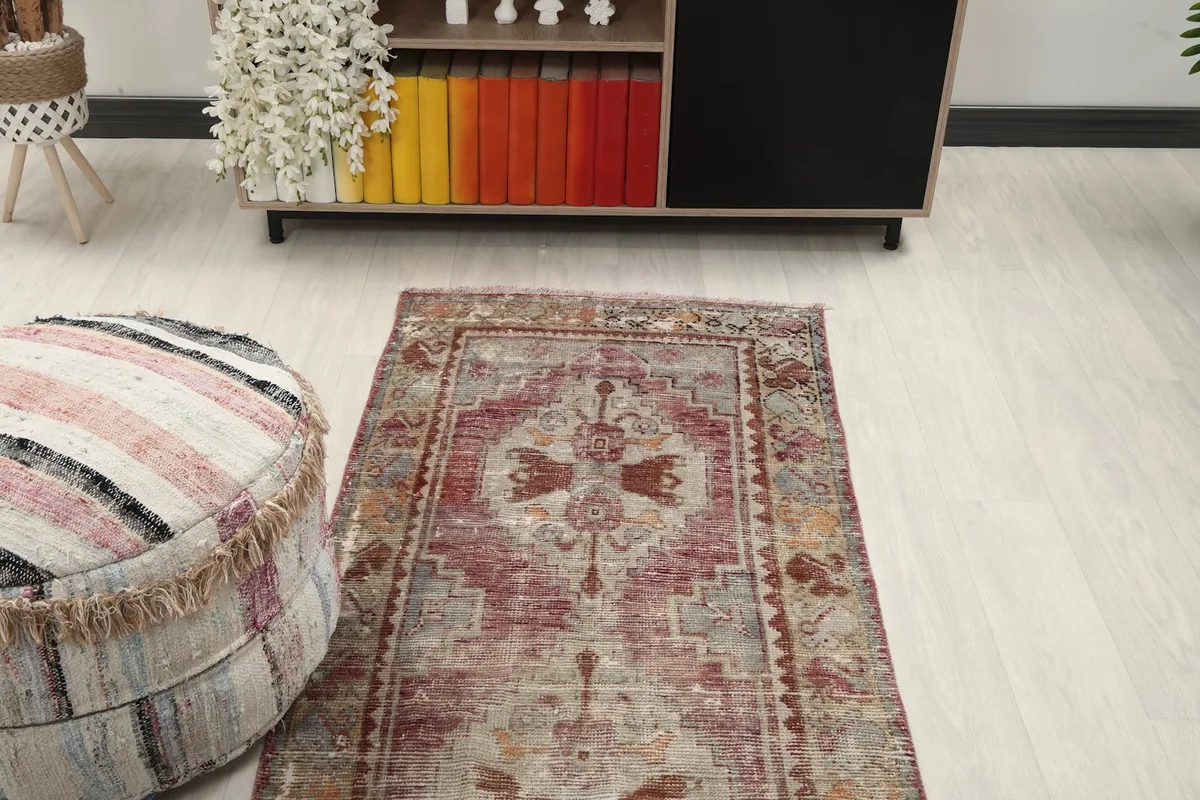 Overhead view of one end of the runner rug, displaying its motifs and the overall distressed appearance.