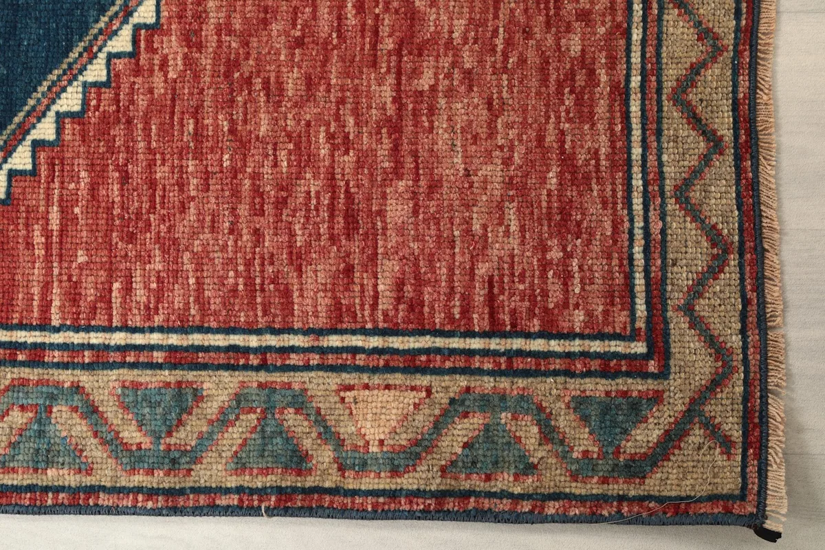 Detail of the rust field and the beige border with green and navy geometric patterns