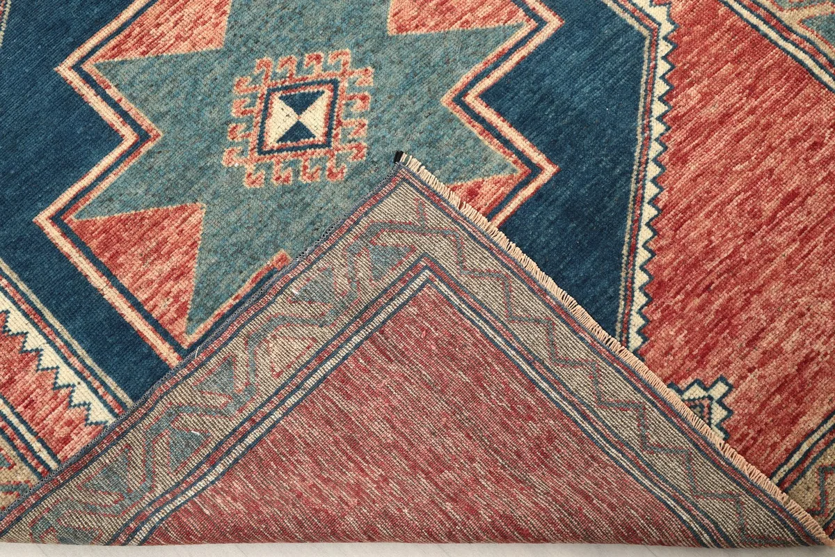 Folded corner of the rug revealing the backside of the hand-knotted wool pile and cotton foundation
