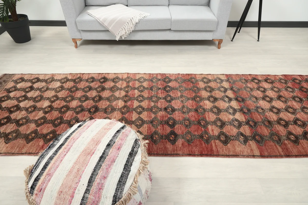 Long view of the Rust Geometric Tribal Runner in a hallway-like setting with an ottoman