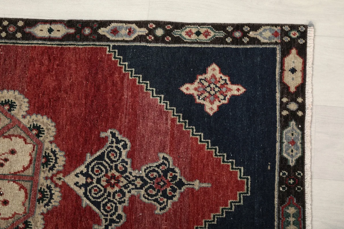 Close-up of the rug's corner, highlighting the navy field, red accent, and border details.
