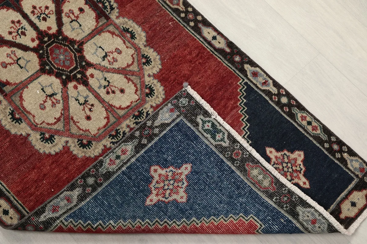 View of the back of the rug, folded to show the hand-knotted construction and fringe.