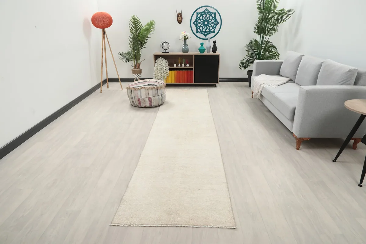 Vintage beige runner rug displayed in a modern living room setting with a gray sofa.