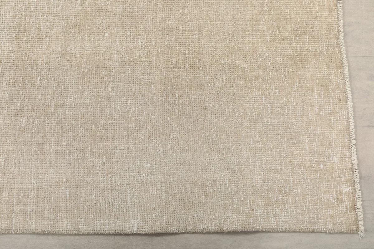 Detailed view of the rug's surface, highlighting the subtle variations in the beige wool pile.