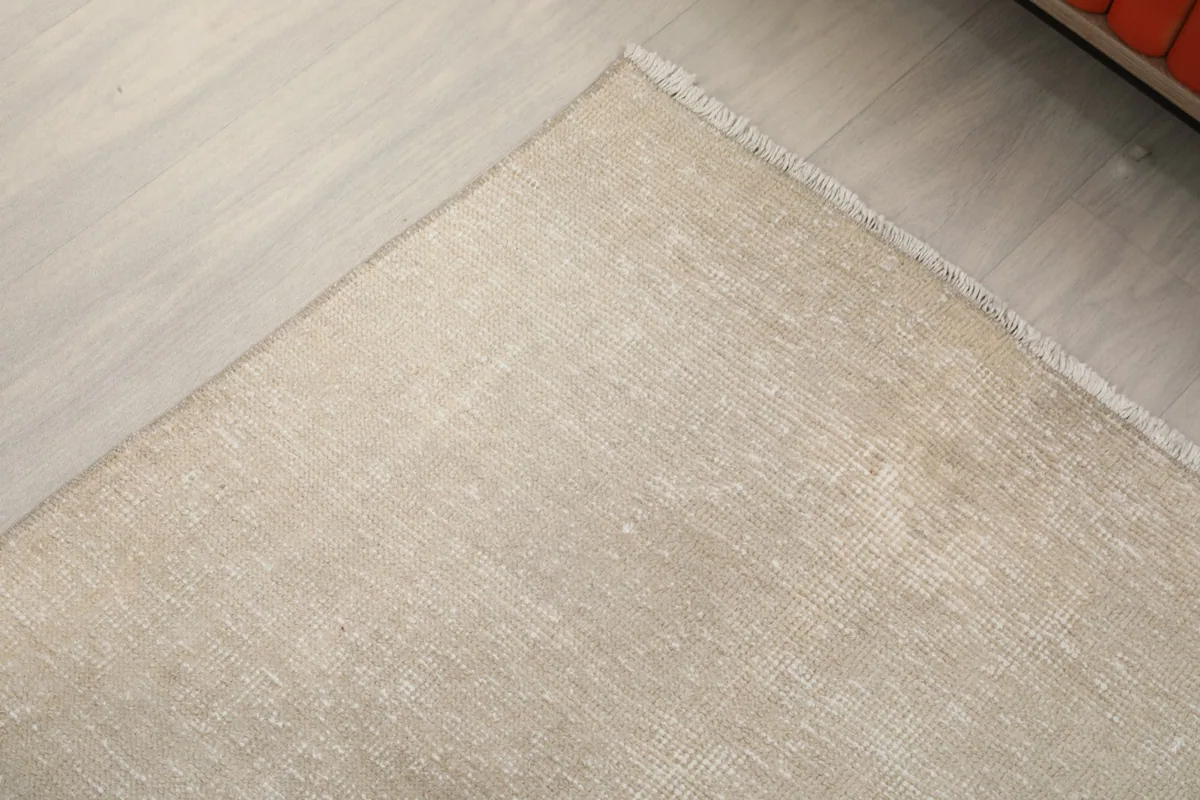 Corner detail of the beige runner rug, showing the edge finish and subtle color variations.