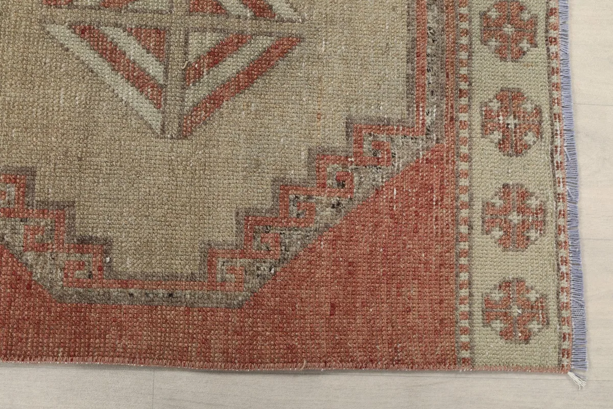 Detailed view of the corner of a tan geometric medallion and the rust field