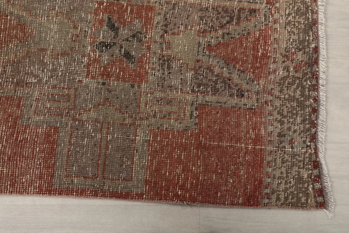 Detailed view of the rug's end, showing the distressed rust and gray tones