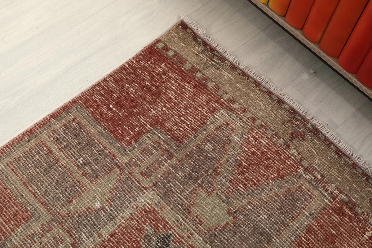 Corner detail of the rug, highlighting the worn edges and faded patterns