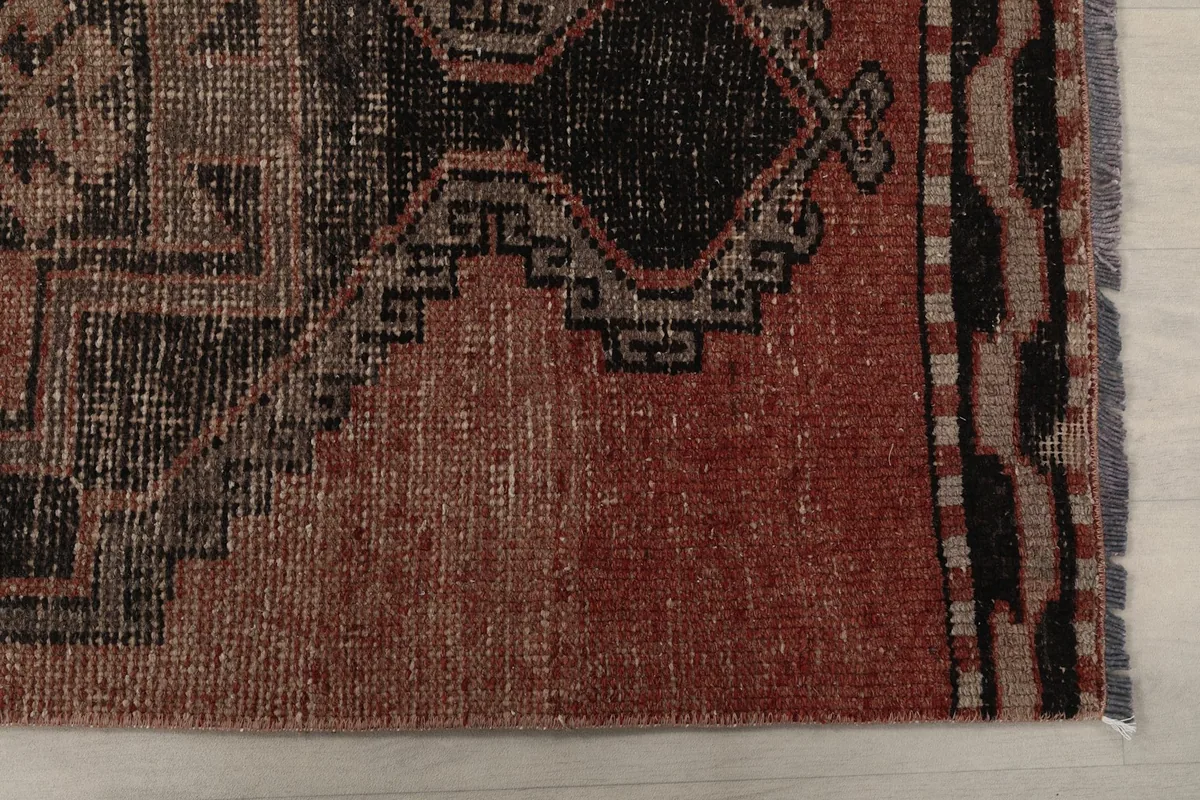 Detail of the rug's edge, showing the rust field and black border patterns