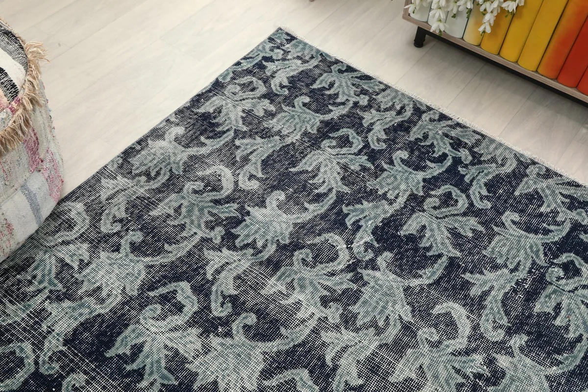 Angled view looking down at the rug, emphasizing the repeating floral design and muted tones.