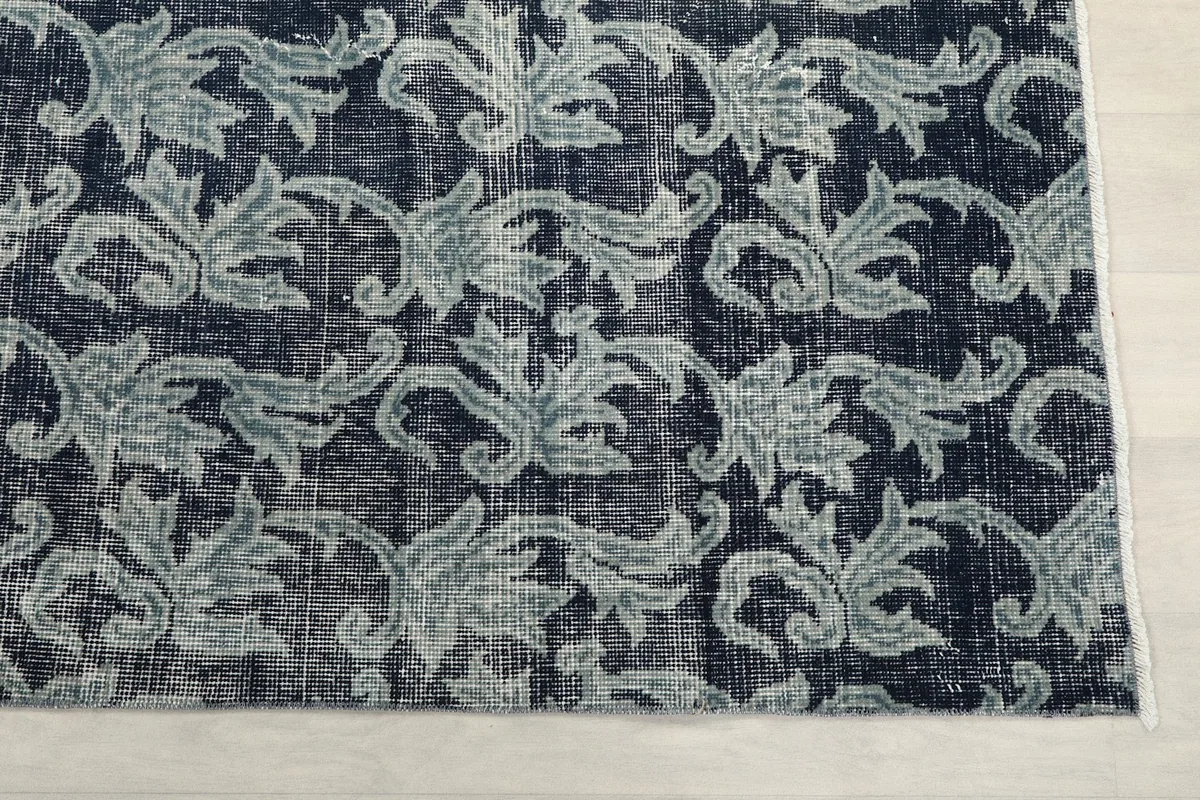 Detailed view of the rug's corner, highlighting the gray floral motifs against the navy background.
