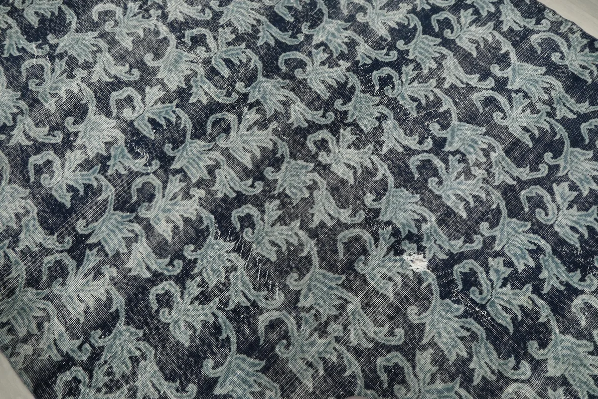Close-up of the distressed texture and floral pattern, showing variations in color and wear.