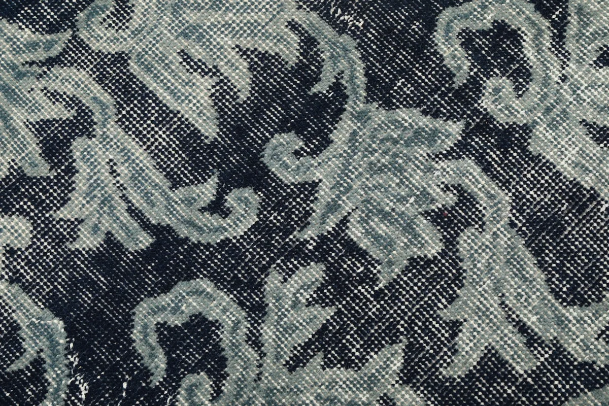 Macro shot of the hand-knotted wool pile, revealing the weave and subtle color shifts.