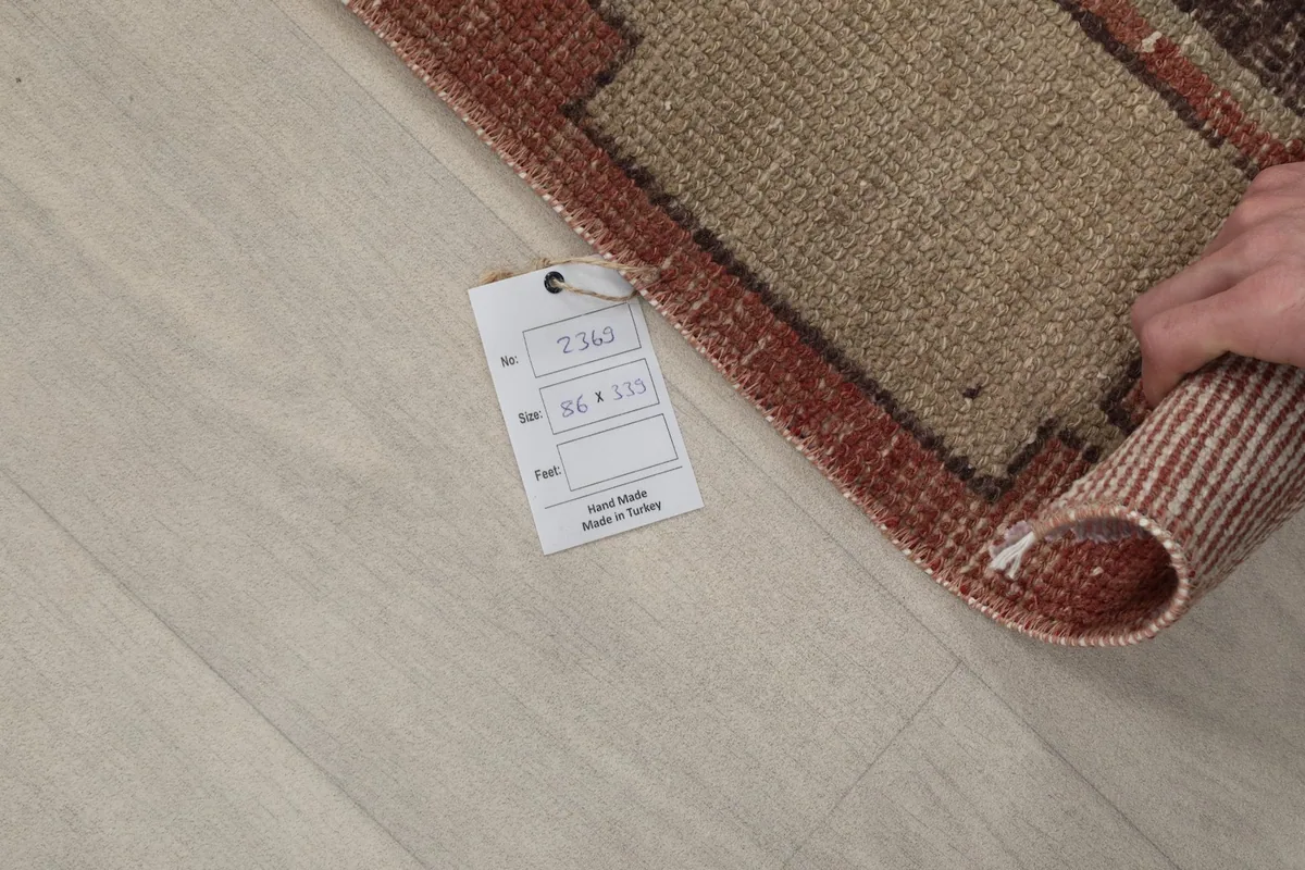 Rug corner rolled up with a product tag showing dimensions and origin