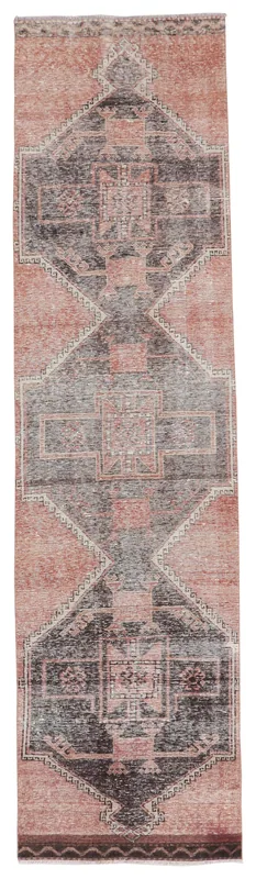 Full overhead view of a vintage rust and charcoal geometric runner rug on a white background