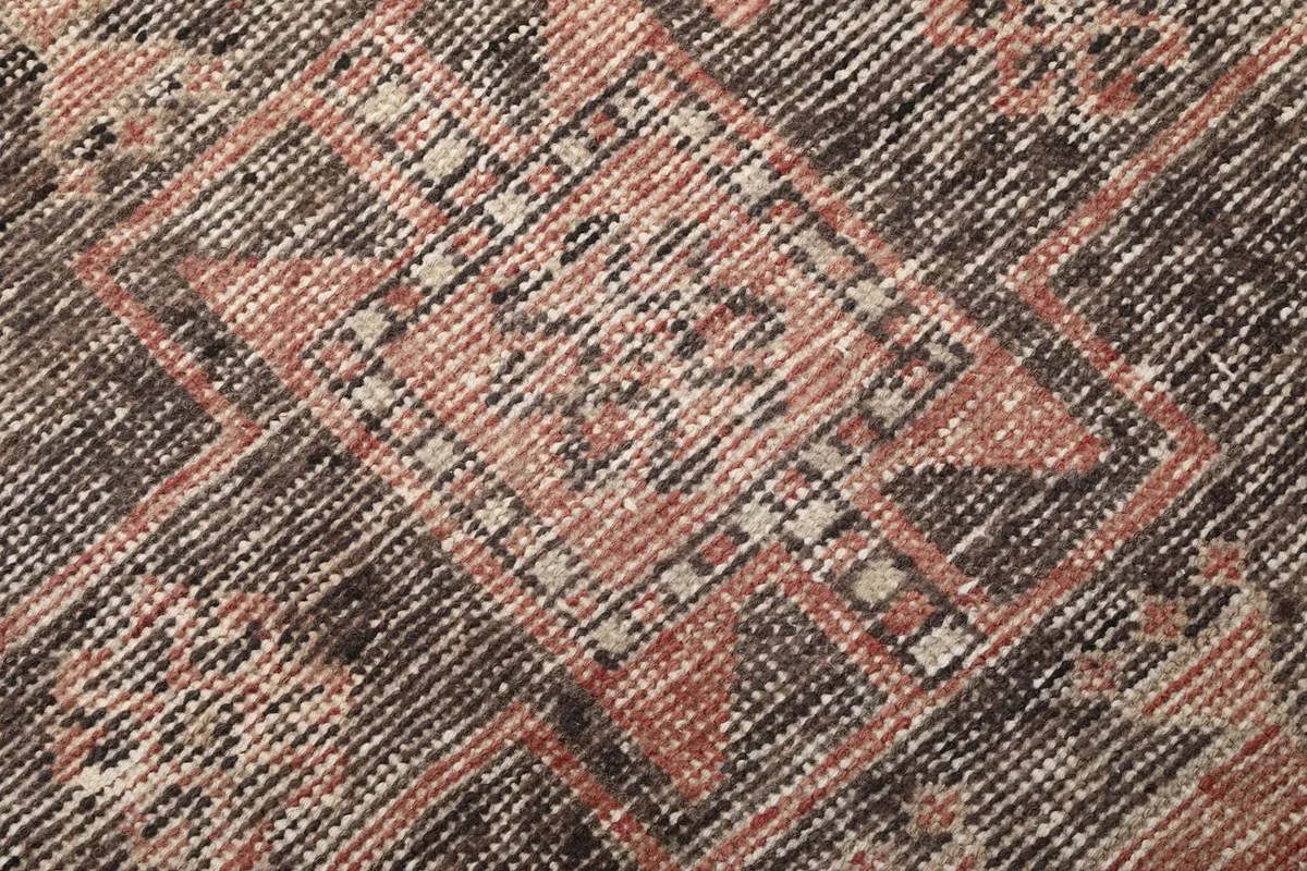 Tight shot showing the low wool pile and intricate hand-knotted details of the rug