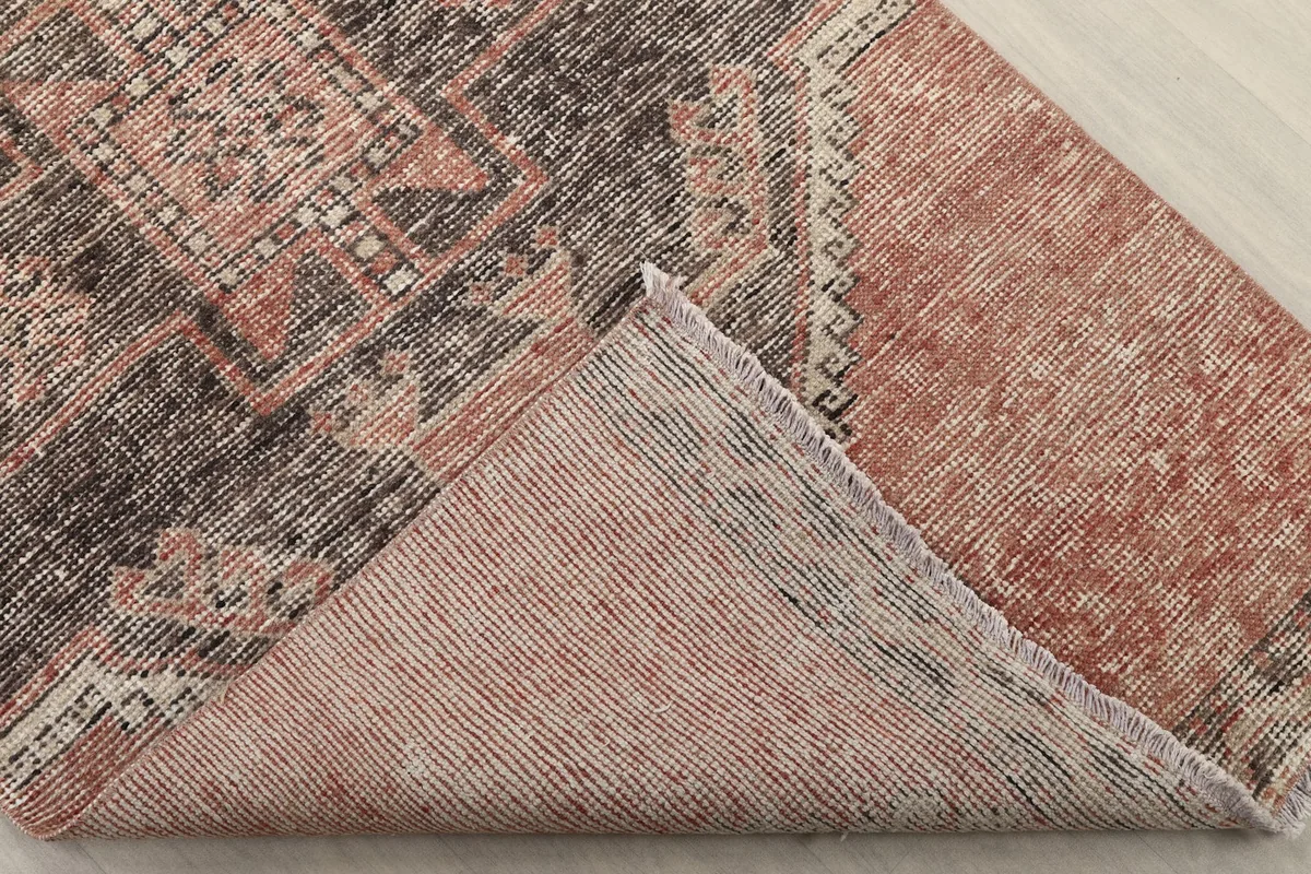 Corner of the rug folded back to reveal the cotton foundation and reverse side of the knots