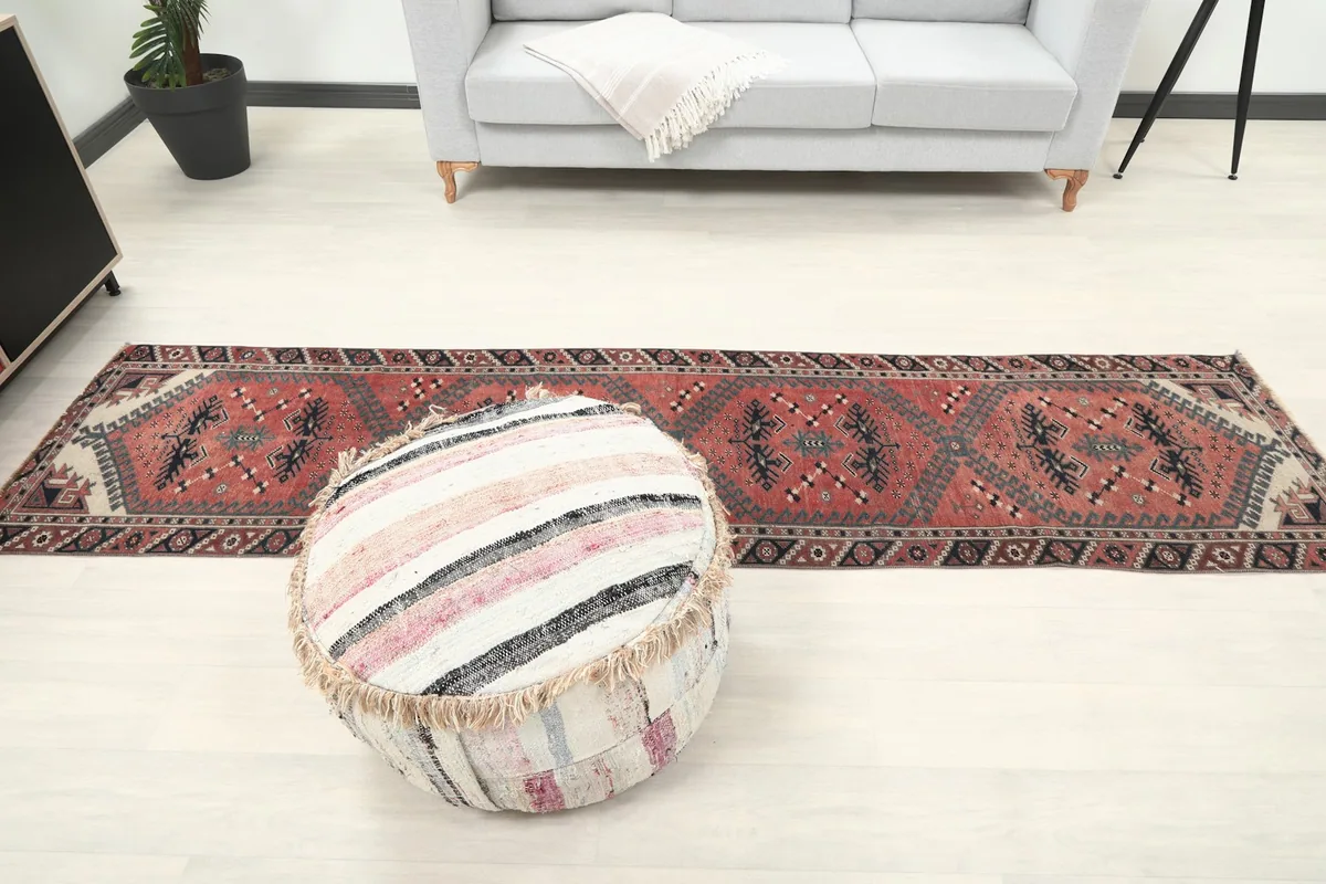 Full length view of the runner rug in a room, positioned with a sofa and pouf.