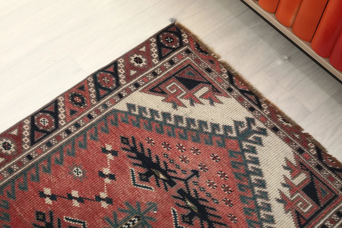 Close-up of the rug's border and corner, detailing the intricate geometric motifs and color blend.