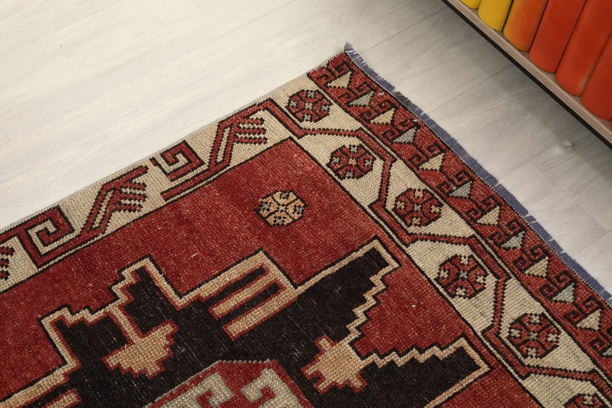 Close-up of the geometric border design and the main rust field of the rug