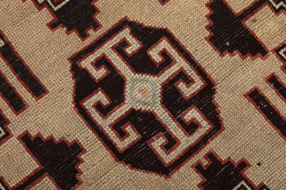 Texture and low pile of the rug, showing the wool fibers and detailed knotting in cream and black
