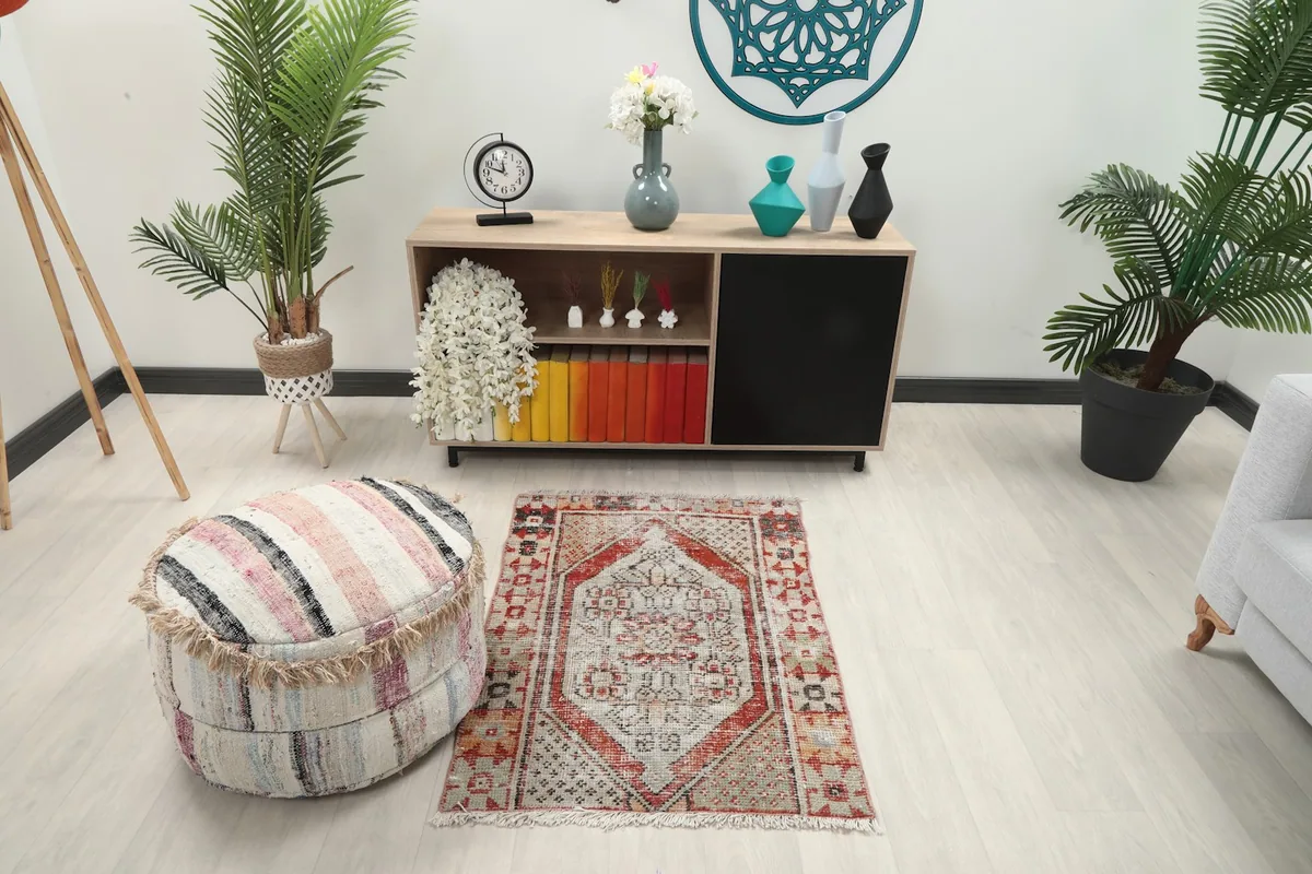Vintage Anatolian rug displayed in a living area with a striped ottoman