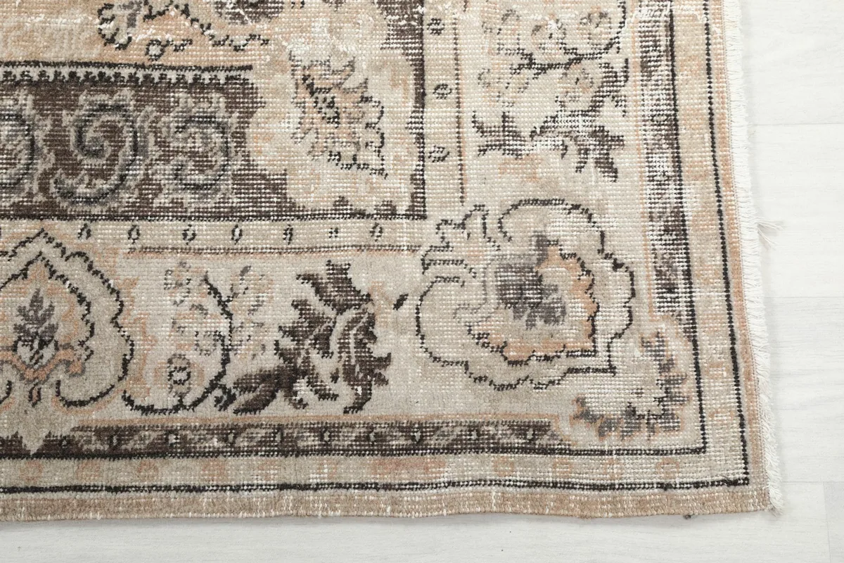 Detail of the rug's corner with border patterns and visible vintage wear