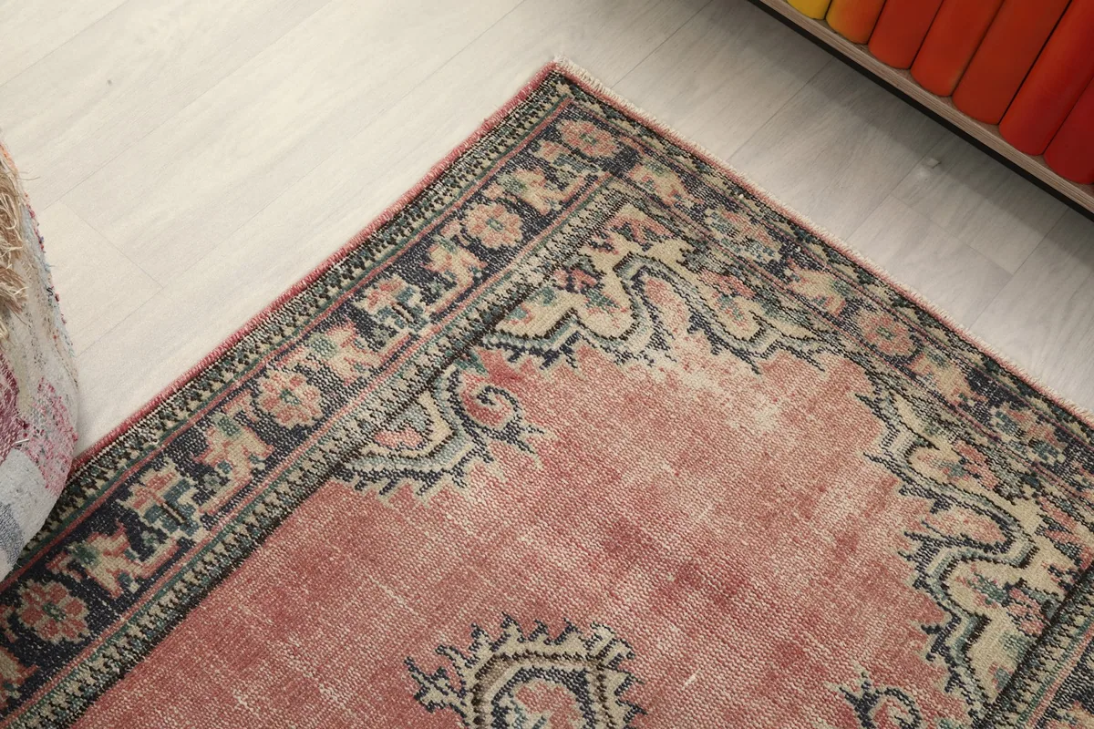 Corner view of the rug, highlighting the border design and faded rose field