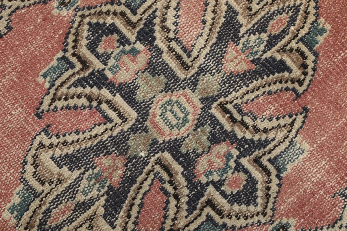 Extreme close-up showing the wool pile texture and faded colors of the medallion motif