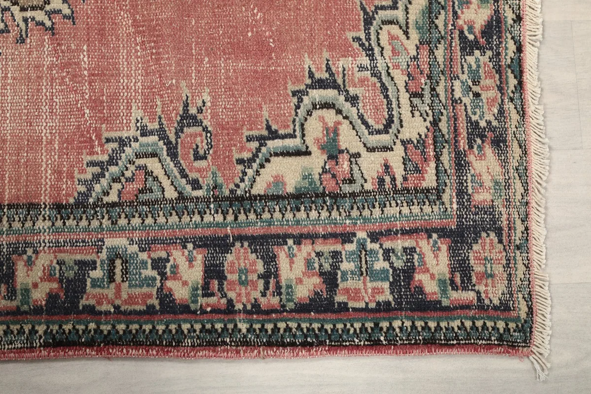 Detailed view of the intricate navy and beige geometric border pattern and fringe