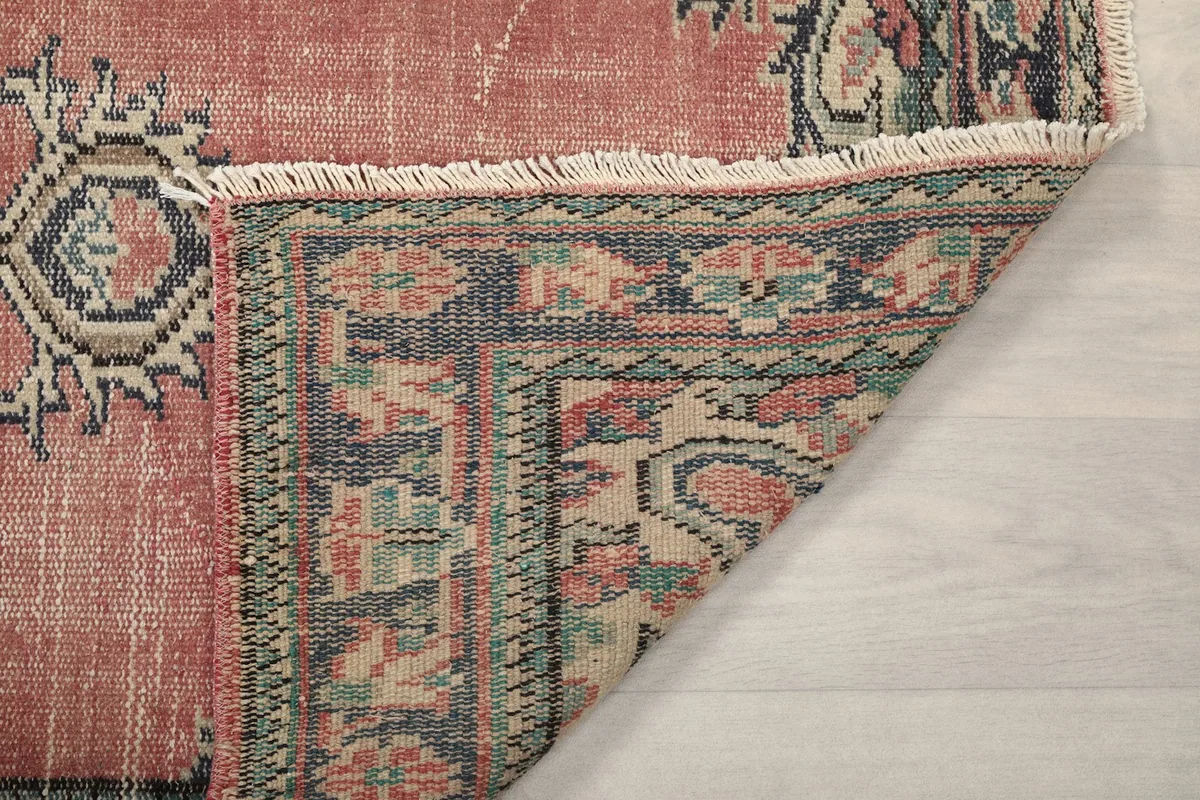 Another view of the rug's folded corner, showing the reverse weave and fringe
