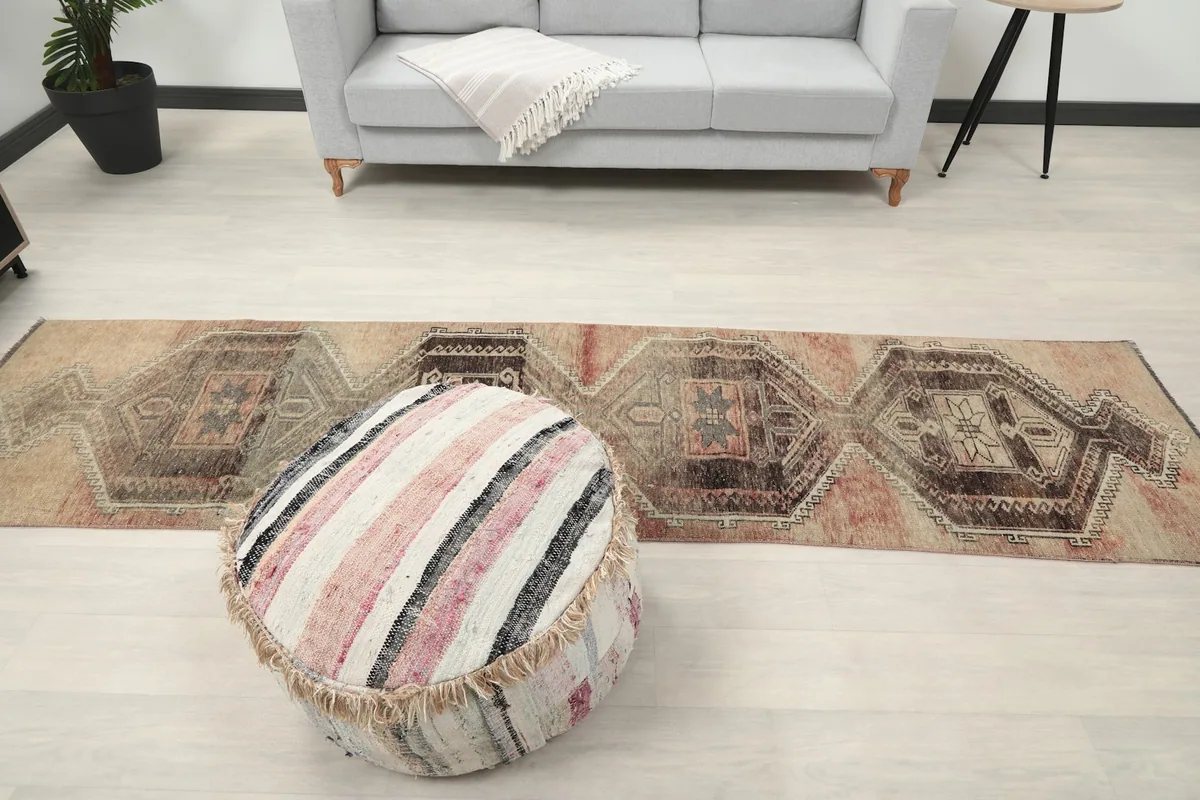 Runner rug extending across a room with a gray sofa and ottoman, showcasing its length.