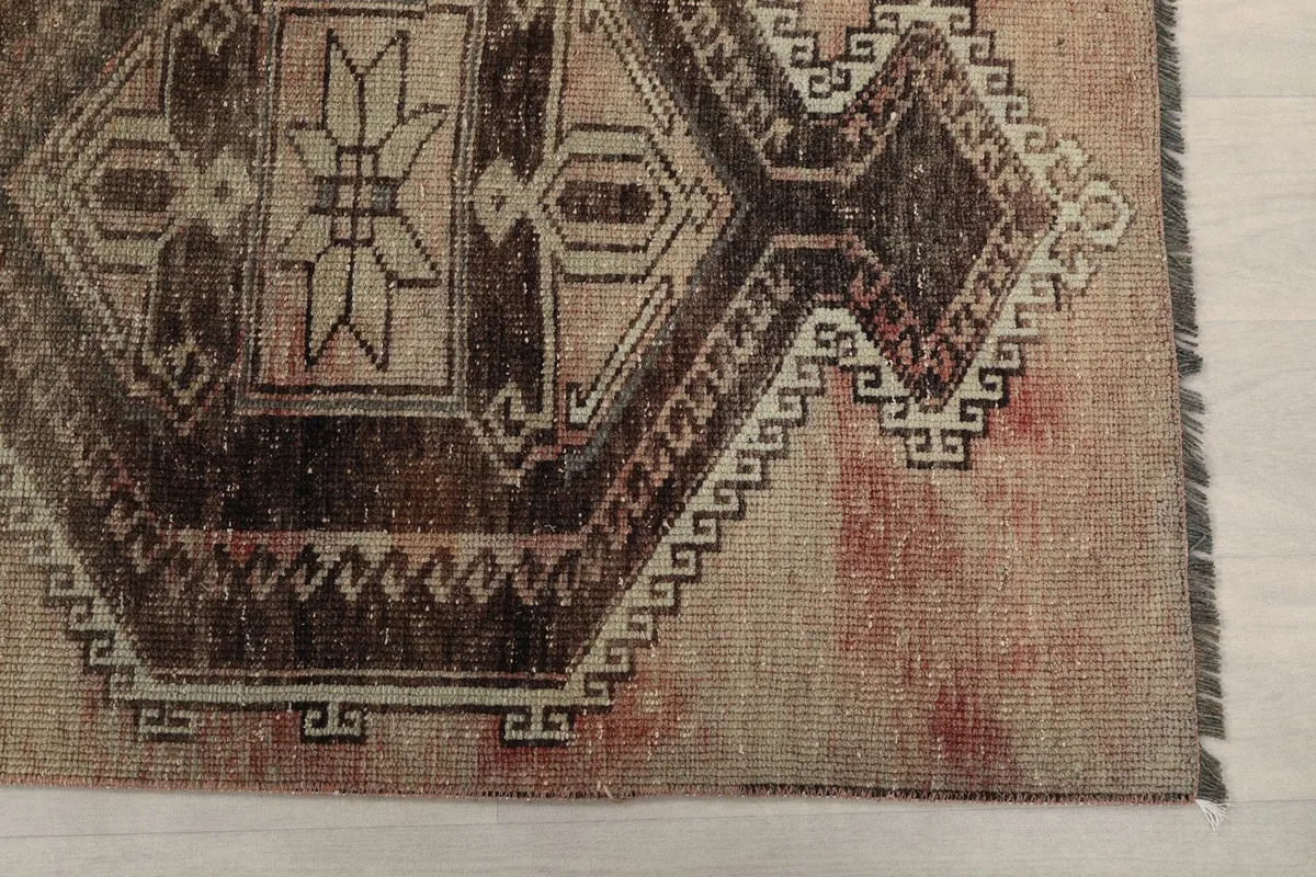 Detailed view of the rug's end, showing the geometric border and slight color variations.