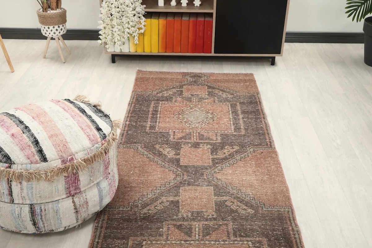 Overhead view of the vintage runner rug in a room, positioned between a sofa and a decorative pouf.