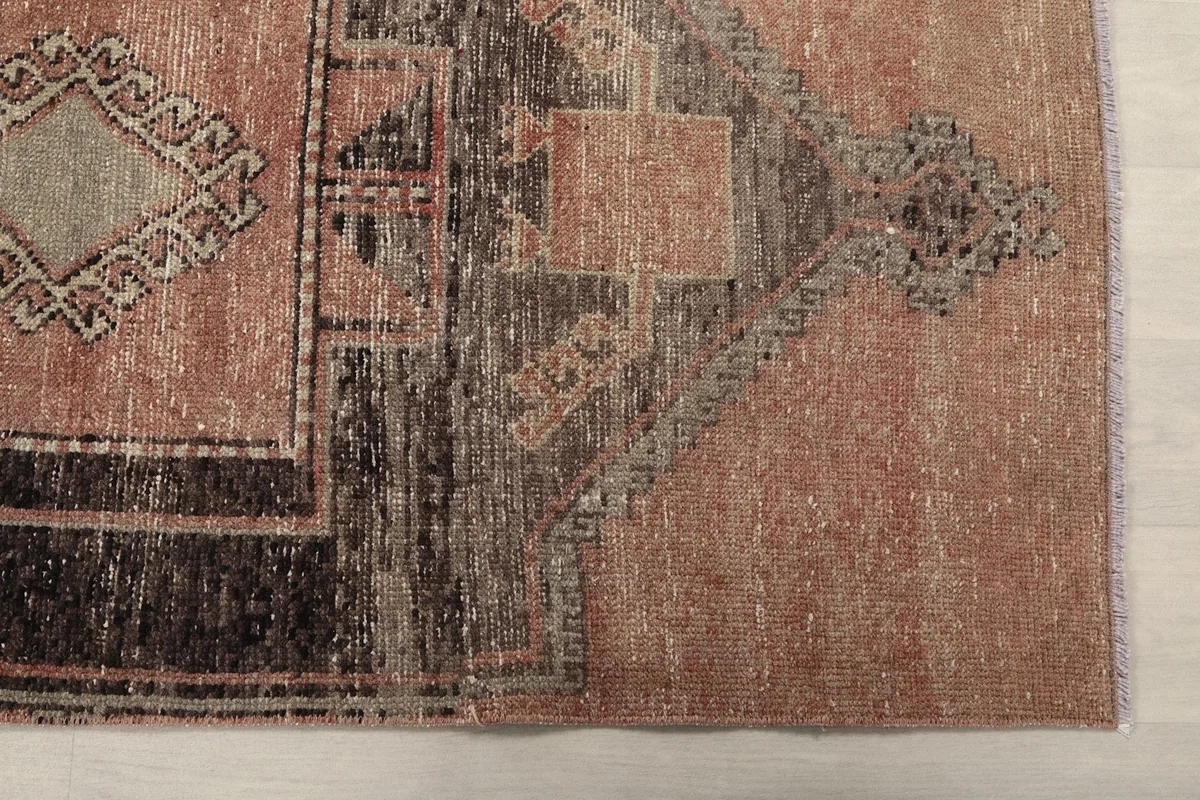 Detailed view of the rug's end, highlighting the rose field and charcoal border with subtle wear.