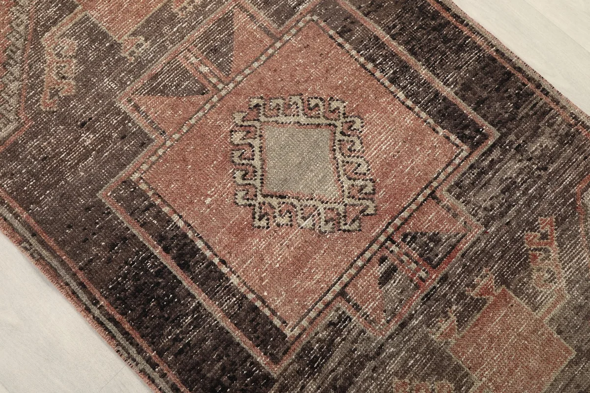 Close-up of a central geometric medallion with gray and rose tones, showcasing the hand-knotted texture.