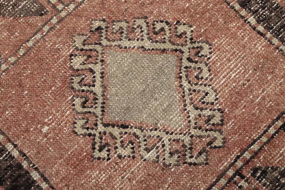 Macro shot of the low pile, revealing the intricate weaving and a square motif with a beige center.