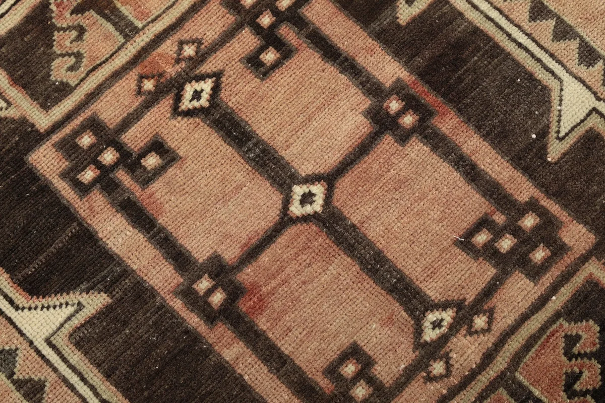 Close-up of a central geometric motif, highlighting the charcoal and beige details on the rose field