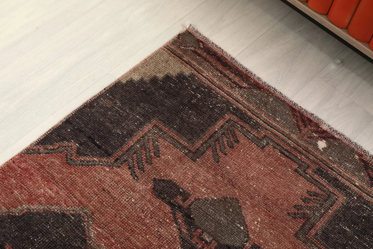 Overhead detail of the rug's end, highlighting the worn edges and tribal-inspired patterns.