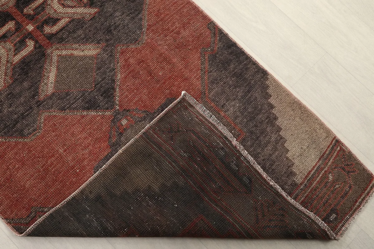 One corner of the runner folded back to show the cotton foundation and reverse side of the rug.