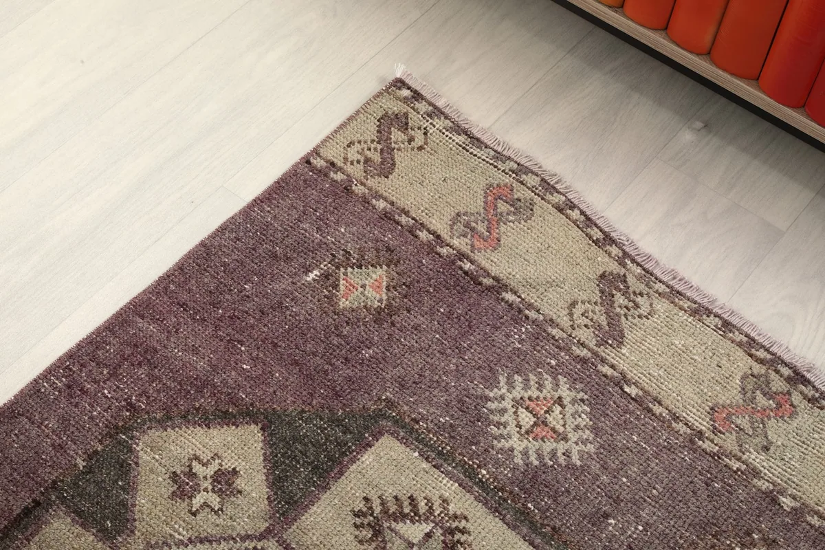 Corner detail showing the beige border with geometric designs and the purple main field