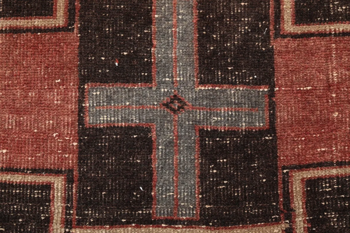 Detailed view of a gray cross-like geometric pattern within a brown section of the rug
