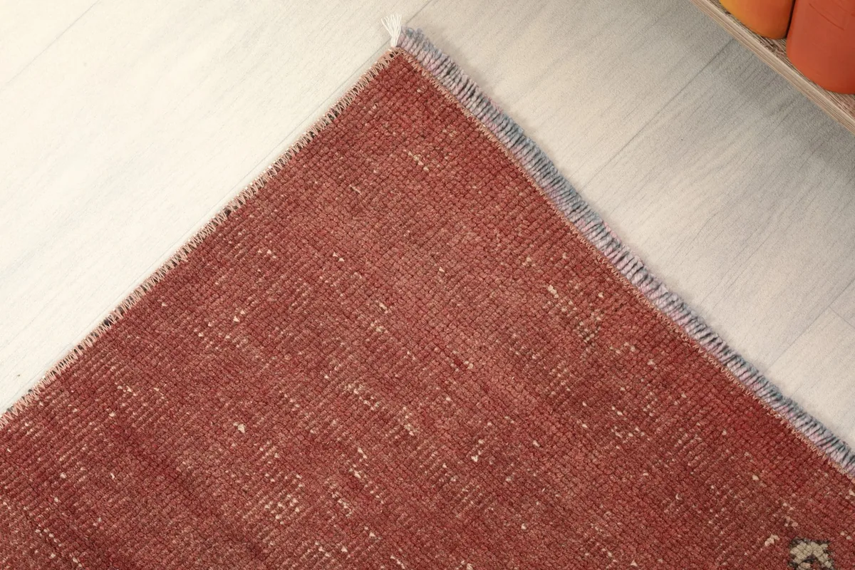 Corner view of the rug's edge, showing the subtle transition from the red field to the short fringe