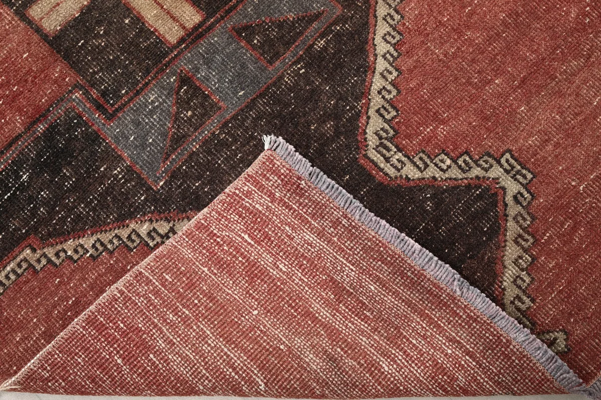 Folded corner of the rug revealing the low wool pile and cotton foundation structure