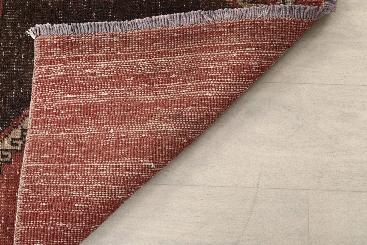 Underside of the rug shown by a folded corner, displaying the hand-knotted cotton foundation