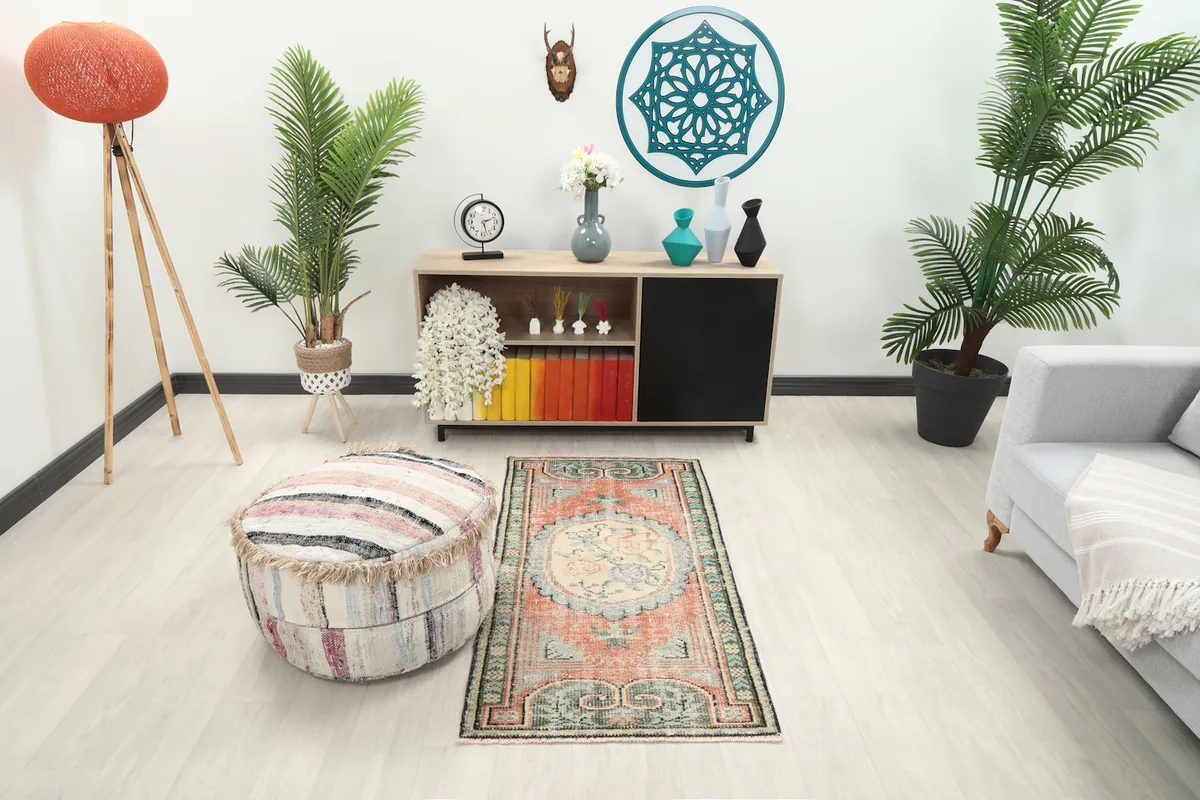 Vintage Anatolian rug displayed in a bright living room setting next to an ottoman
