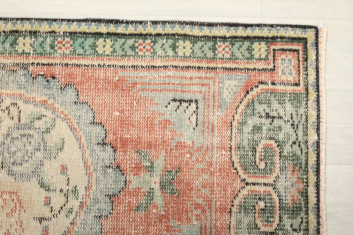 Detailed view of the upper right corner of the rug, showing green border and rust field